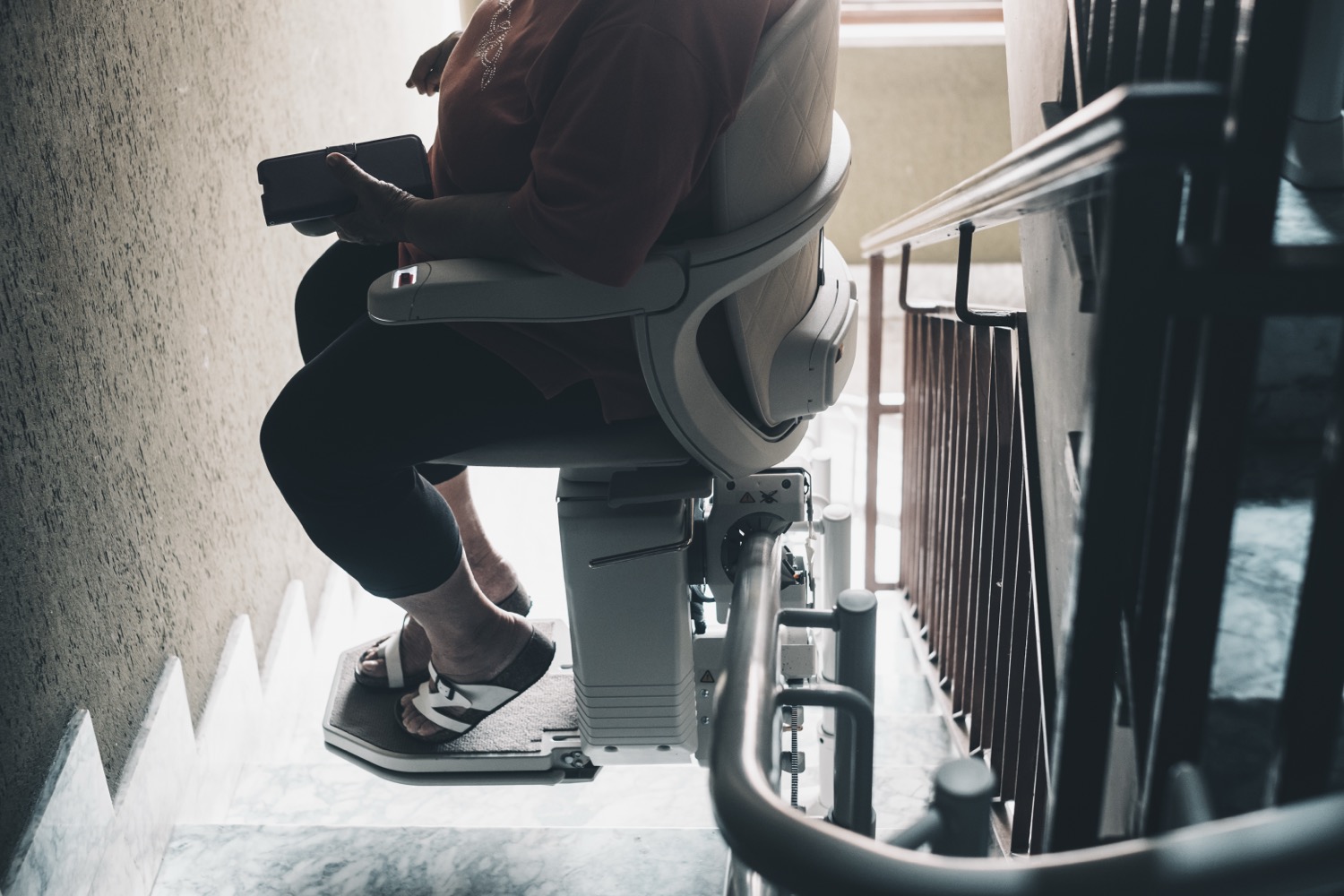alte frau braucht moderne unterstutzung um zu hause nach oben zu gehen konzept fur altersprobleme ein elektrisch motorisiertes stuhlleben fur menschen mit behinderungen auf einer mit teppich ausgelegten treppe einem wohnheim